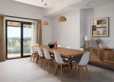 a dining room with a wooden table and white chairs at Masia Cal Noia - Rural Villas in Castellví de la Marca