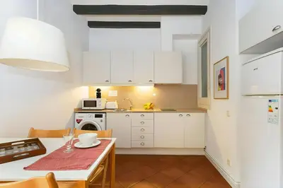 a small kitchen with white cabinets and a table at Tranquil Cozy with balcony Plaça Catalunya. RI. in Barcelona