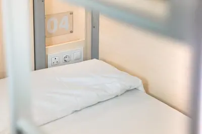 a bed in a room with an alarm clock on the wall at Urbany Hostel Barcelona in Barcelona
