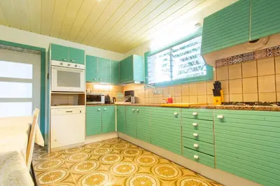 a kitchen with green cabinets and white appliances at Mediterranean heaven with sea views in Alella
