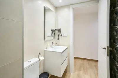 a white bathroom with a sink and a mirror at Tr3sor 11 in Calella