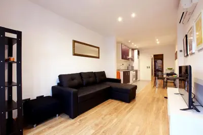 a living room with a black couch and a kitchen at Apartment Park&Beach Deluxe in Barcelona