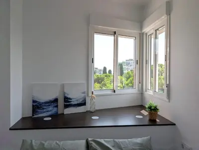 a living room with a table and two windows at Apartament Hotel - El Barco in Hospitalet de Llobregat