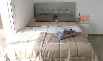 a bed with two towels on it in a bedroom at Apartament Hotel - El Barco in Hospitalet de Llobregat