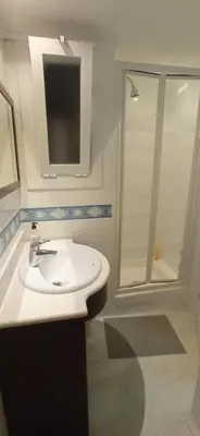 a white bathroom with a sink and a shower at Quiet cozy apartment near beach in Sitges