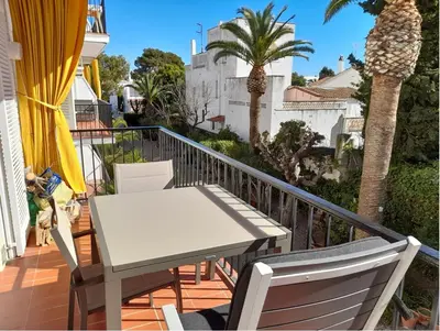 a white table and chairs on a balcony with palm trees at Quiet cozy apartment near beach in Sitges