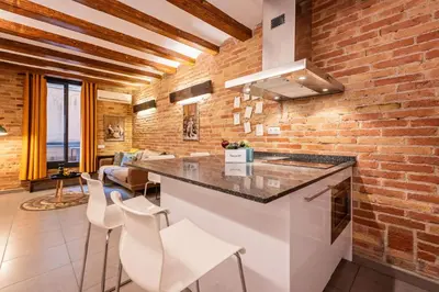 a kitchen with a brick wall and a counter with stools at Sweett - Gallery Poble Sec in Barcelona