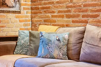 a couch with pillows on it with a brick wall at Sweett - Gallery Poble Sec in Barcelona
