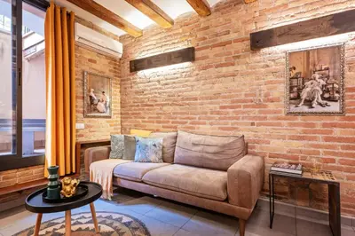 a living room with a couch and a brick wall at Sweett - Gallery Poble Sec in Barcelona