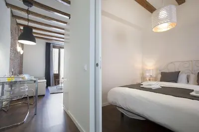 a white bedroom with a large bed and a bathroom at Tendency Apartments - Sagrada Familia in Barcelona