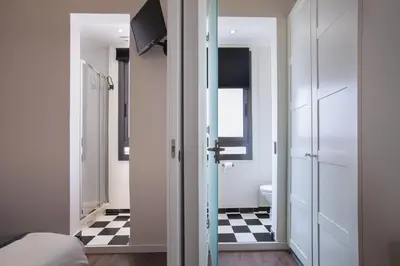 a room with a bed and a bathroom with a checkered floor at Tendency Apartments - Sagrada Familia in Barcelona