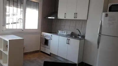 a kitchen with white cabinets and a sink and a refrigerator at Fasten in Barcelona