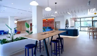 a cafeteria with a wooden table and stools at Holiday Inn Express & Suites Barcelona - Sabadell by IHG in Sabadell