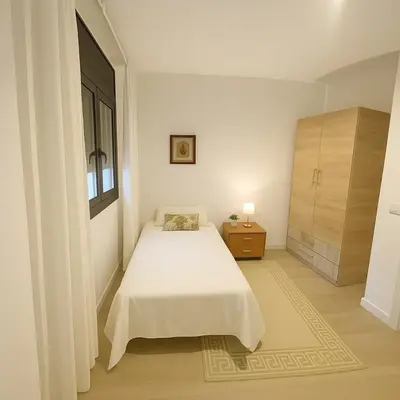 a white bedroom with a bed and a window at D&G casas in El Prat de Llobregat