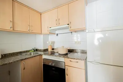 a kitchen with wooden cabinets and a white refrigerator at Estudio con encanto en Barcelona in Barcelona