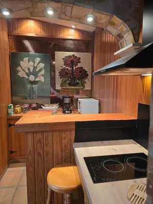 a kitchen with wooden cabinets and a counter with a stove at Can Marisu, Casita privada in Cabrils
