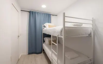 a room with three bunk beds and a blue curtain at Stay U-nique Roger Llúria in Barcelona