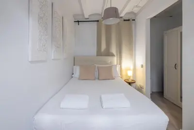 a white bedroom with a large white bed with two pillows at Stay U-nique Roger Llúria in Barcelona