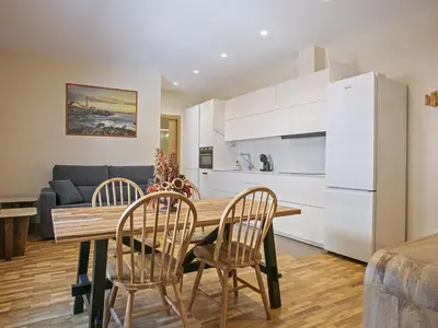 a kitchen and living room with a wooden table and chairs at Winahost Sabadell Buxeda in Sabadell