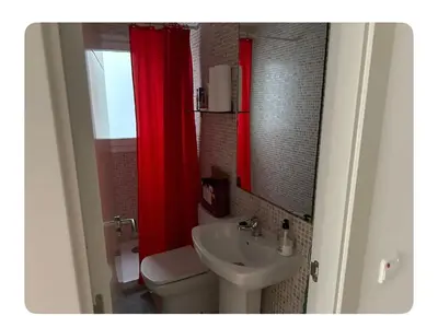 a bathroom with a sink and a toilet and a red shower curtain at Lilli apartment in Sitges