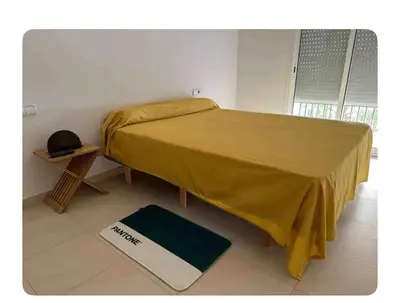 a bed with a yellow blanket and a scale on the floor at Lilli apartment in Sitges