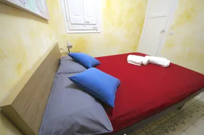 a bed with blue and red sheets and blue pillows at Plaza España Central Apartment in Barcelona