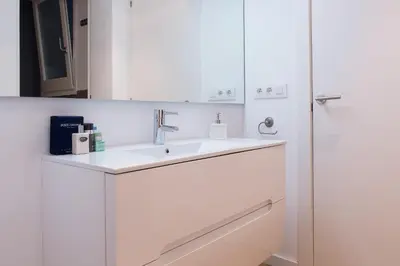 a white bathroom with a sink and a mirror at Bright Industrial Loft Barcelona Center in Barcelona