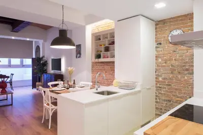 a kitchen with white cabinets and a brick wall at Bright Industrial Loft Barcelona Center in Barcelona