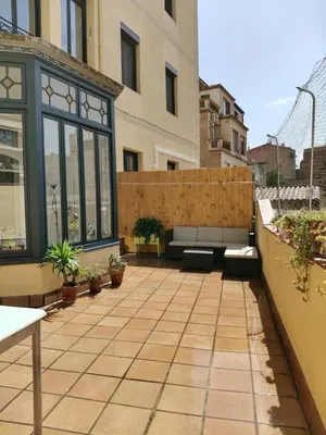 a patio with benches and plants on a building at Pis històric modernista al centre de Manresa in Manresa