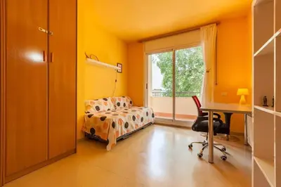 a bedroom with a bed and a desk and a window at La Cantonada in Sant Pere de Ribes