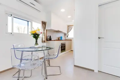 a white kitchen with a glass table and chairs at St. Antoni sky lounge in Barcelona