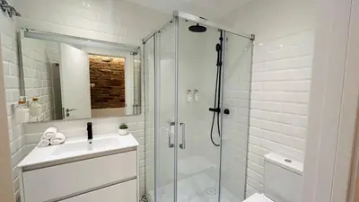 a white bathroom with a shower and a sink at Bajos con encanto by Prestigi in Terrassa