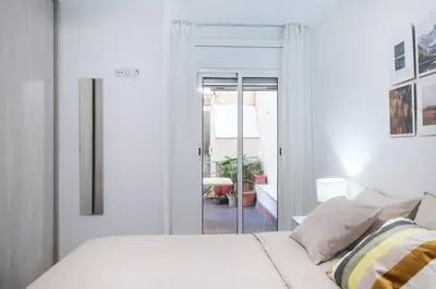 a white bedroom with a bed and a sliding glass door at Homenfun Barcelona Los Bunkers in Barcelona