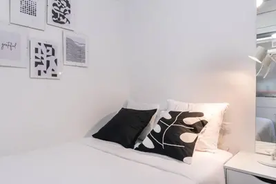 a white bed with black and white pillows on it at Homenfun Barcelona Los Bunkers in Barcelona