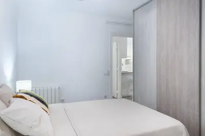 a white bedroom with a bed and a mirror at Homenfun Barcelona Los Bunkers in Barcelona