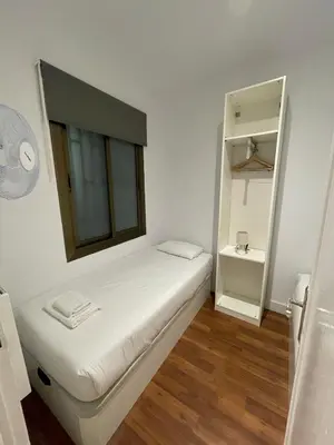 a small white room with a bed and a mirror at Practical, 3 double bedrooms, 7' Sagrada Familia in Barcelona