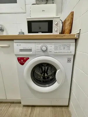a washing machine with a microwave on top of it at Practical, 3 double bedrooms, 7' Sagrada Familia in Barcelona