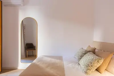 a bedroom with a bed with a mirror and a chair at Barcelona - Gracia P-B in Barcelona