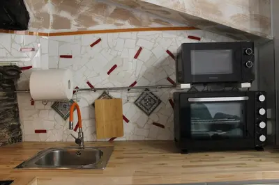 a kitchen with a microwave and a television and a sink at 3-Story Gaudi Building with Montserrat Stone in Monistrol