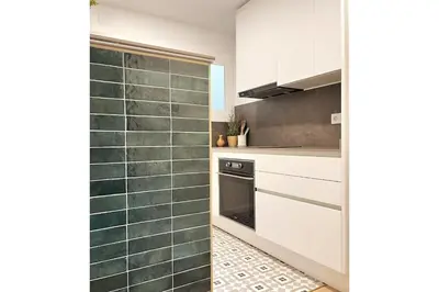 a kitchen with white cabinets and green tiles at Sunny & remodeled Apartment in Sant Boi del Llobregat