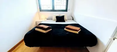 a bedroom with a black bed with two pillows on it at Great apartment with a pool on the beach in Barcelona in Badalona