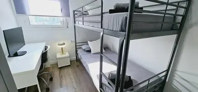 a dorm room with two bunk beds and a desk at Ideal for families on the beach in Barcelona with a pool in Badalona