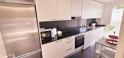 a kitchen with white cabinets and a stainless steel refrigerator at Ideal for families on the beach in Barcelona with a pool in Badalona