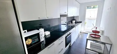 a kitchen with white cabinets and a black counter top at Ideal for families on the beach in Barcelona with a pool in Badalona