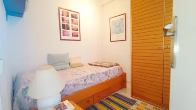 a small bedroom with a bed and a lamp at Cosy flat in pretty seaside town in Sitges