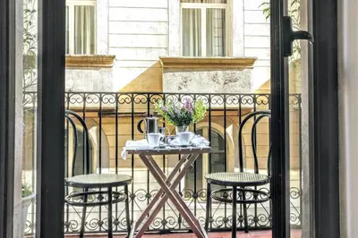 a table on a balcony with two chairs and flowers at La Rambla spacious 3BR monthly rental - Parsifal in Barcelona