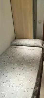 a bed in a room with a white bedspread with flowers at Habitación en piso compartido in Terrassa