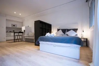 a bedroom with a large bed and a kitchen at Bcn - Loft Parc Guell in Barcelona