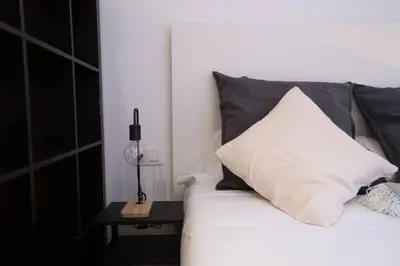 a bed with a black and white pillow and a table at Bcn - Loft Parc Guell in Barcelona