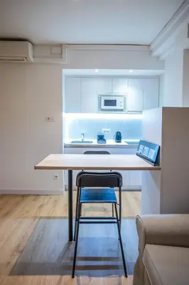a kitchen with a table and a blue chair at Bcn - Loft Parc Guell in Barcelona